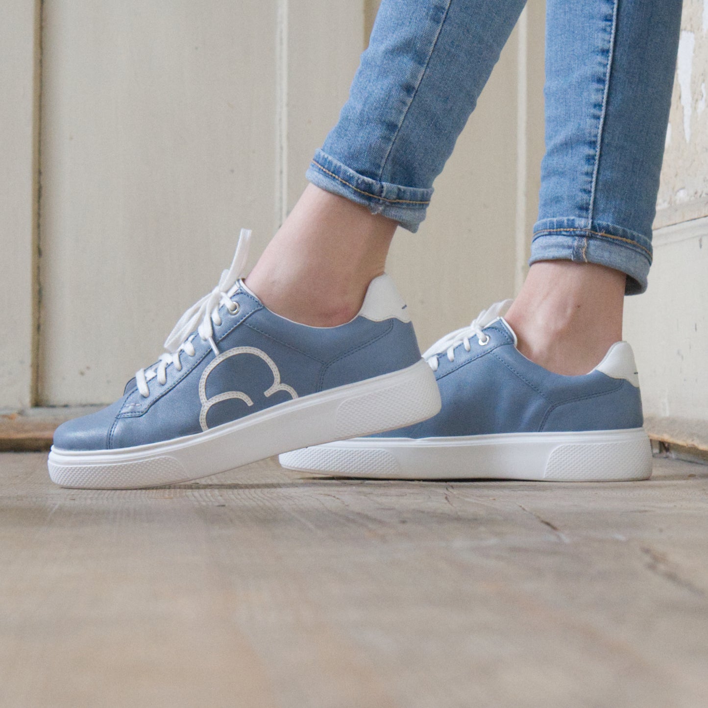 "Frauenfüsse mit CYBRUS Sneaker 49er denim weiss an die Wand angelehnt"