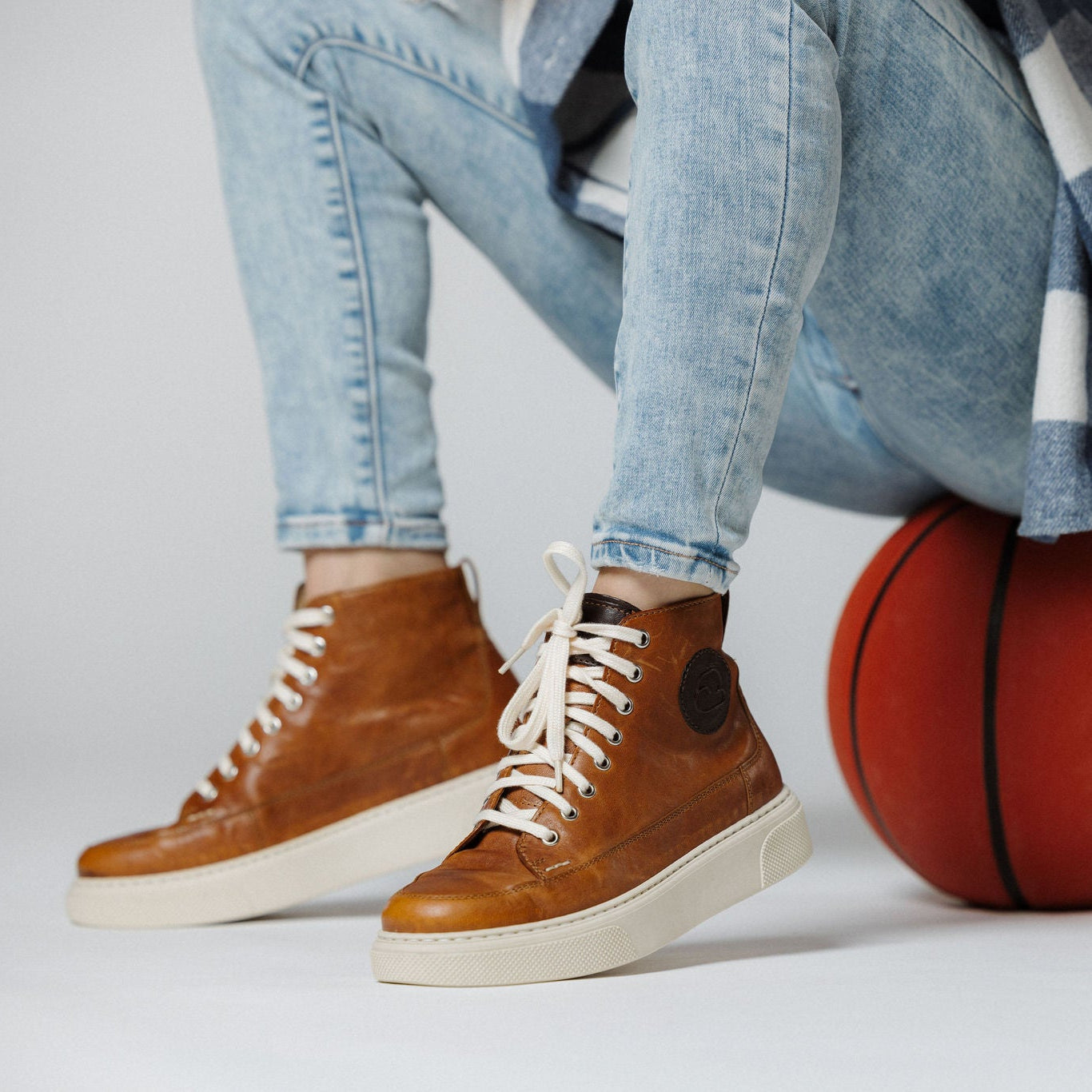 "Frau auf einem Basketball sitzend mit dem CYBRUS Sneaker 51er in hellbraun"