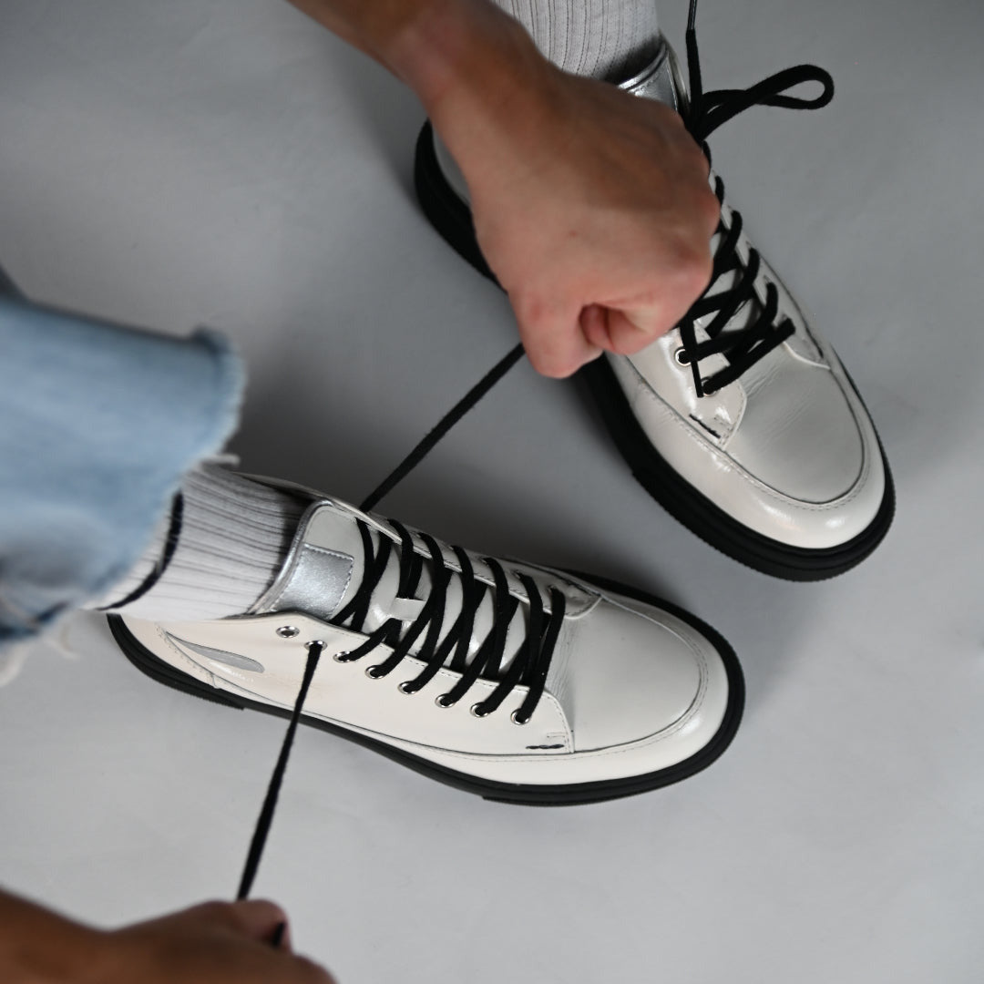 "Person bindet den CYBRUS Sneakers 51er in weiss"