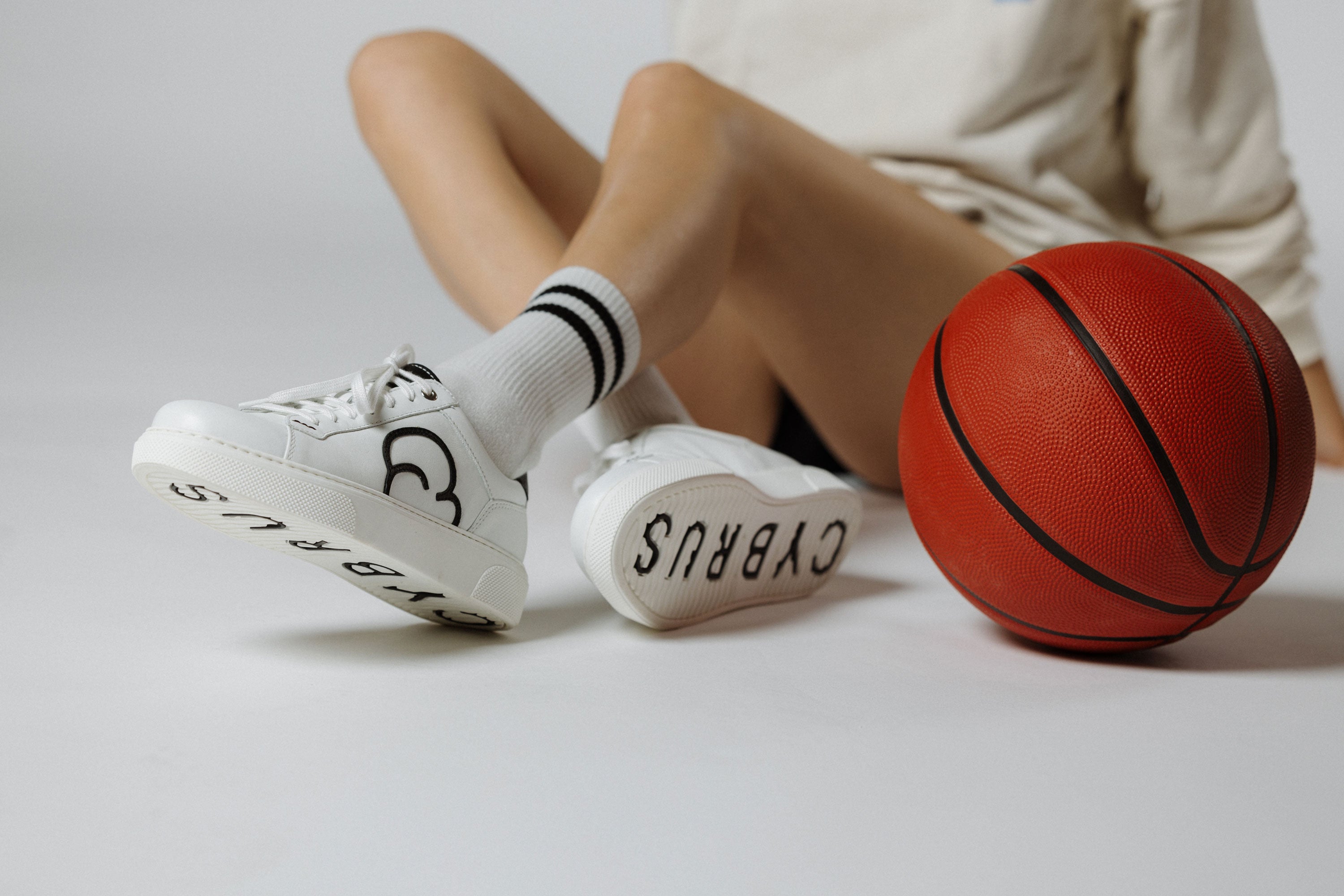 "Frauenbeine mit CYBRUS Sneakers 49er weiss schwarz und einem Basketball"