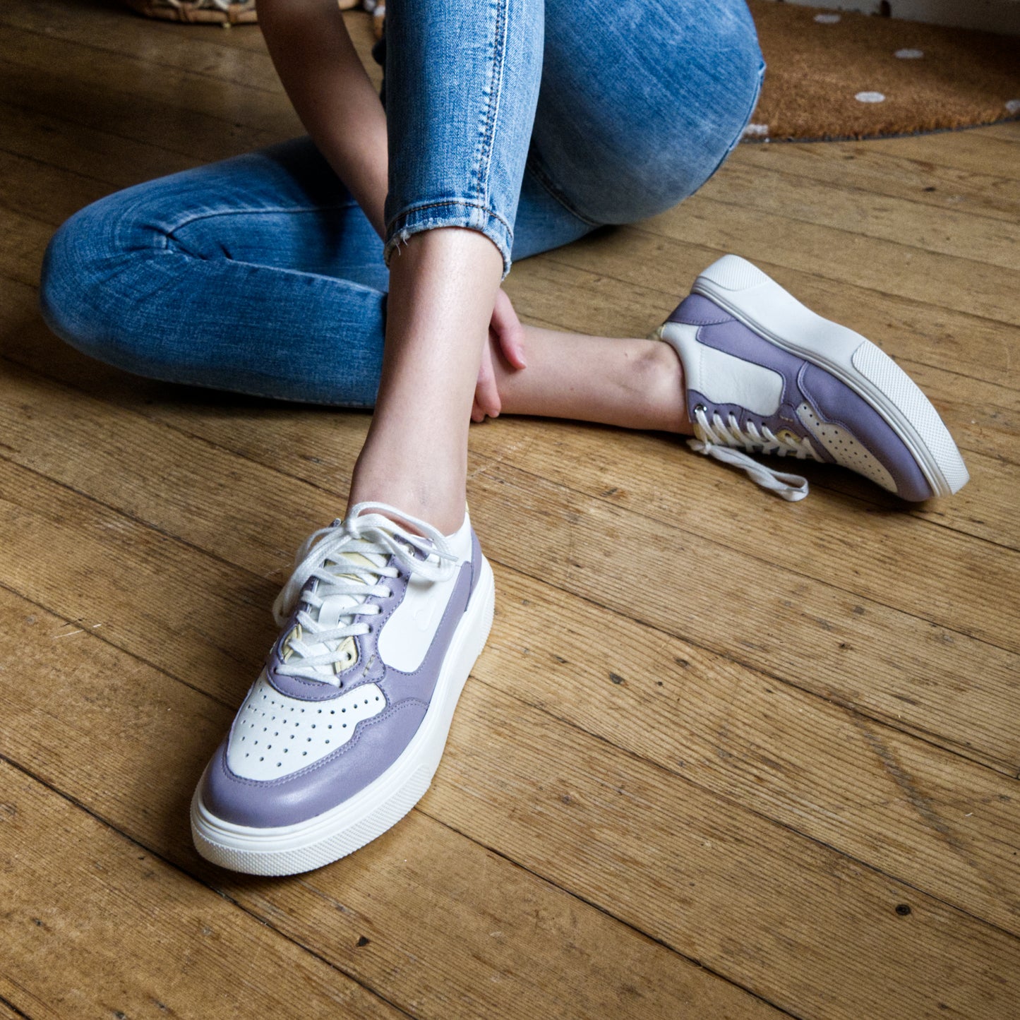 "Frau am Boden sitzend mit CYBRUS Sneaker Haula lila weiss"