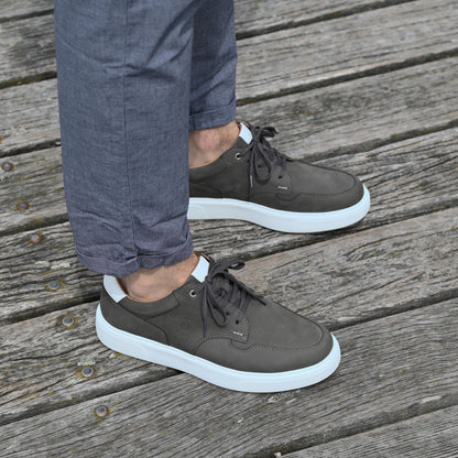 Ein Mann trägt CYBRUS Sneaker Nold grau auf einem Holzsteg