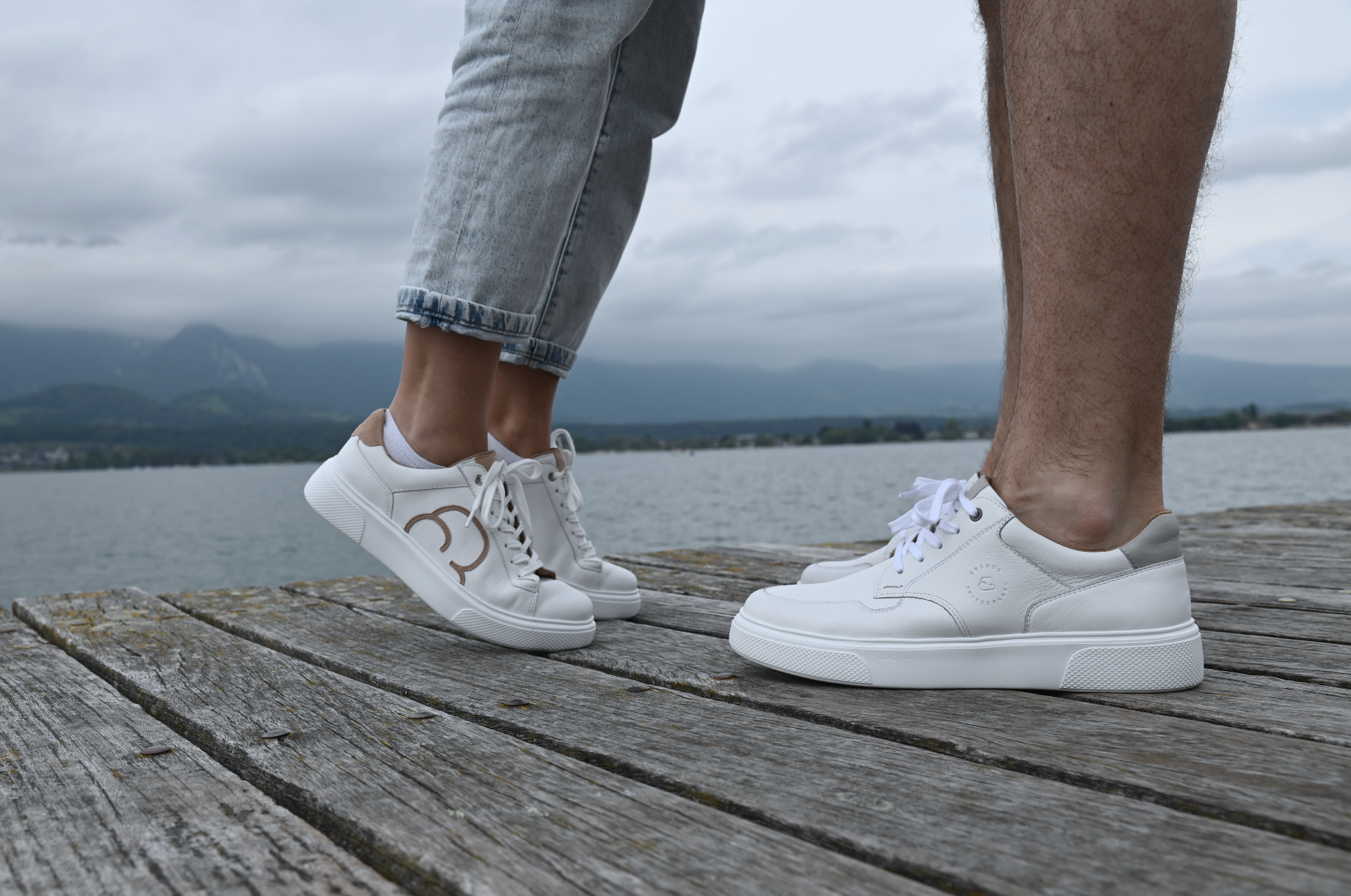 Ein Paar auf einem Holzsteg mit weissen CYBRUS Sneakers.